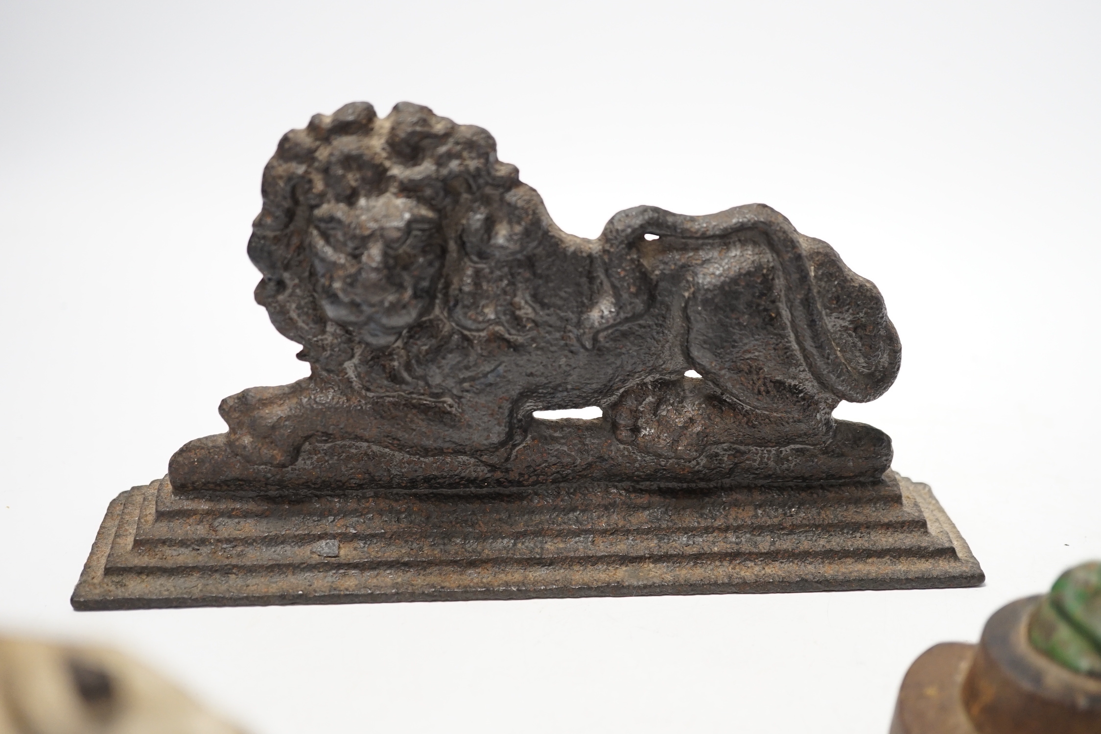 Two cast iron lion door stops and a painted dog door stop, 21cm wide